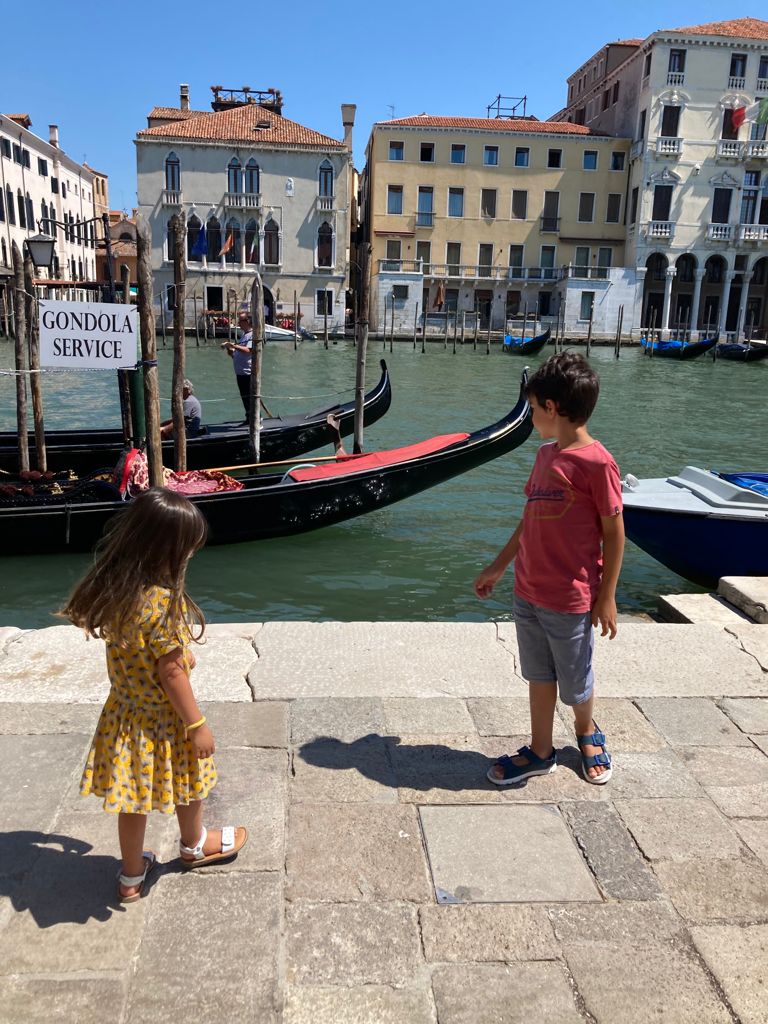 kids close to gran canal with gondolas behind them in a sunny day